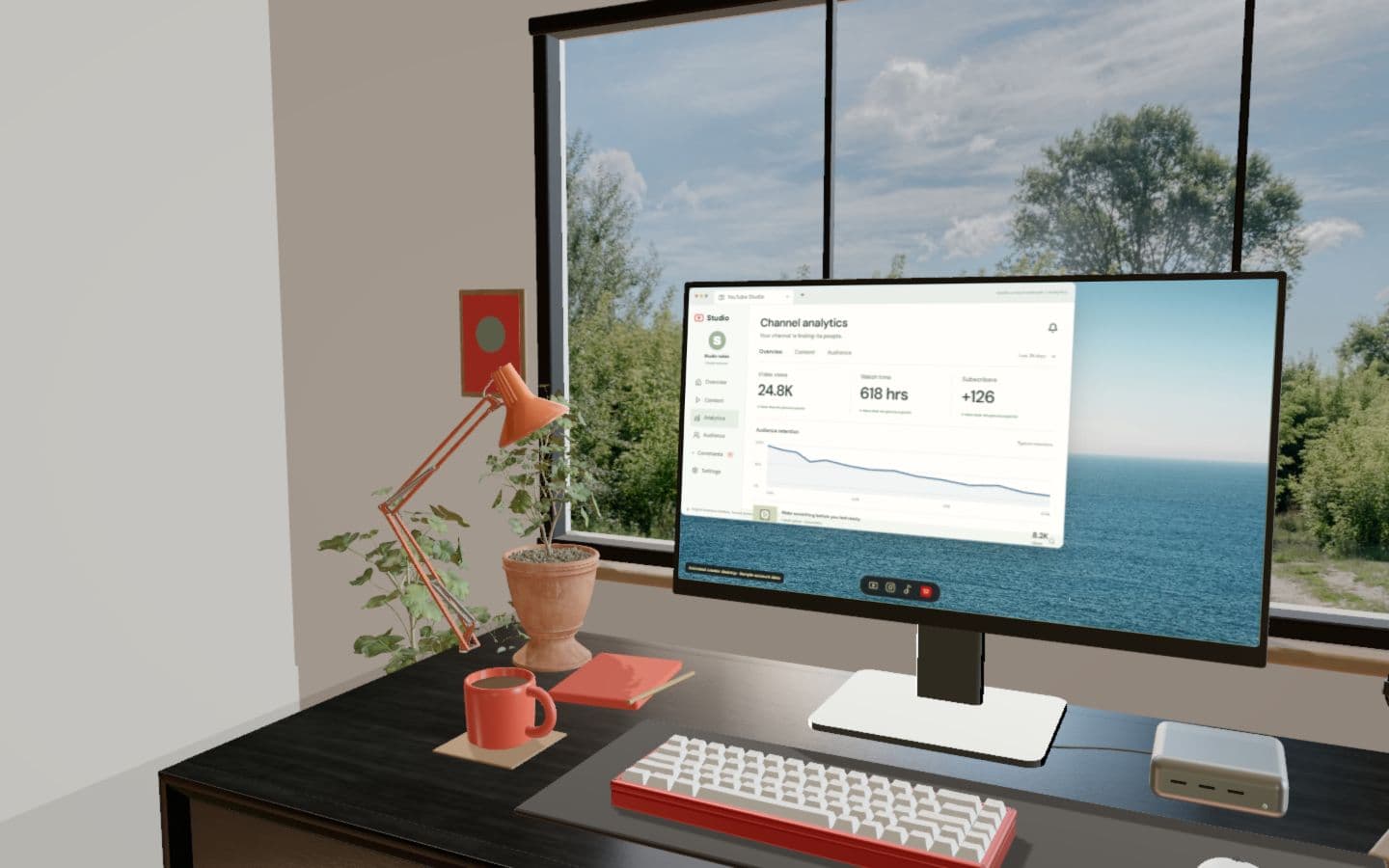 Modern creator studio with a premium monitor, red keyboard, textured desk and bright architectural surroundings